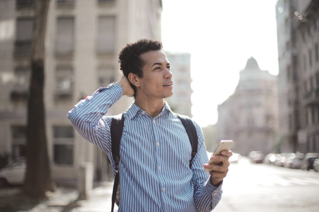 Uomo pensieroso che usa lo smartphone per strada