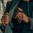 a man holding a wallet and a watch